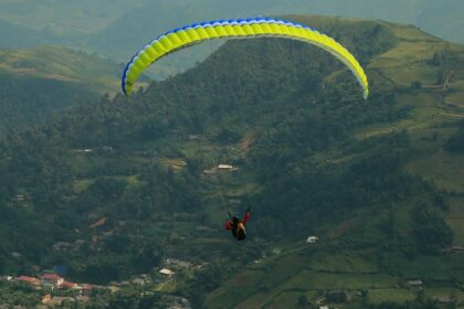 A tourist paragliding in Leh amidst the hills, valleys and green terrains of this lush landscape