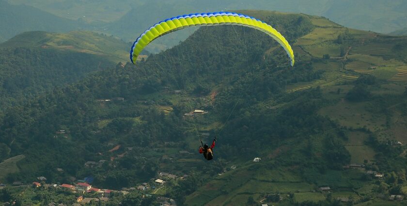 A tourist paragliding in Leh amidst the hills, valleys and green terrains of this lush landscape