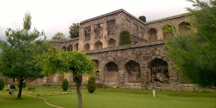 An image of Pari mahal with traditional architecture, finely cut trees, green grass