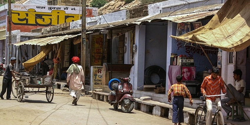 People walking and a child cycling in the streets of Samode village in Rajasthan