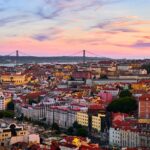 A wide view of the beautiful skyline of Lisbon with the 25 de Abril Bridge in the background.