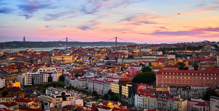 A wide view of the beautiful skyline of Lisbon with the 25 de Abril Bridge in the background.