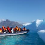 An image of a boat navigating icy waters near Greenland, with icebergs in the background