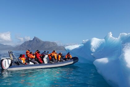 An image of a boat navigating icy waters near Greenland, with icebergs in the background