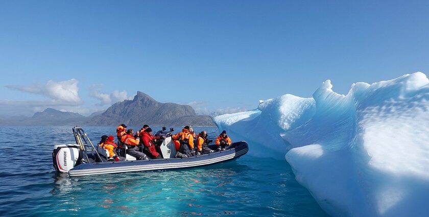 An image of a boat navigating icy waters near Greenland, with icebergs in the background