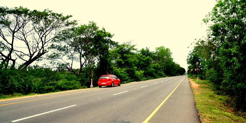 An image of a woman inside a car, driving on a road, resembling the route from Pondicherry to Chidambaram.