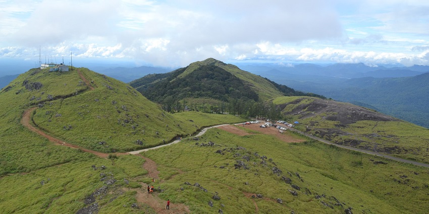 An image showing a winding road with dense vegetation through the hills of Ponmudi, Kerala