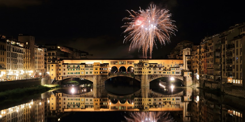 A beautiful show of fireworks is reflected in a river, one of the best places to visit in Florence.