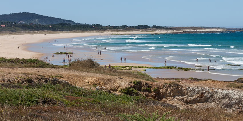Praia das Furnas, a sandy beach with gentle waves, along the coast under a clear blue sky