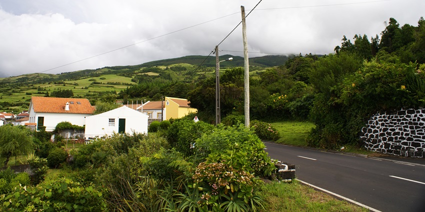 A landscape with a road curving through the scene, colorful houses and lush green hills