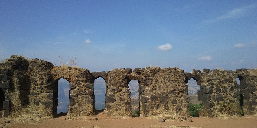 An image of an ancient stone wall with arched windows of the Raigad fort, one of the most significant Indian historical forts.