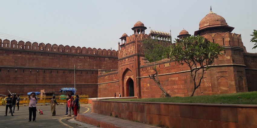 An image of the Red Fort in Delhi, amongst the popular historical forts in India, with tourists and a clear sky in the background.