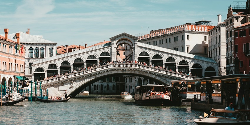 Couples admire an eye-catching view from Rialto Bridge, a top site to visit in Venice.