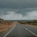 A dark road curves into the distance under a stormy sky similar to road trips in India