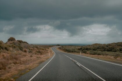 A dark road curves into the distance under a stormy sky similar to road trips in India