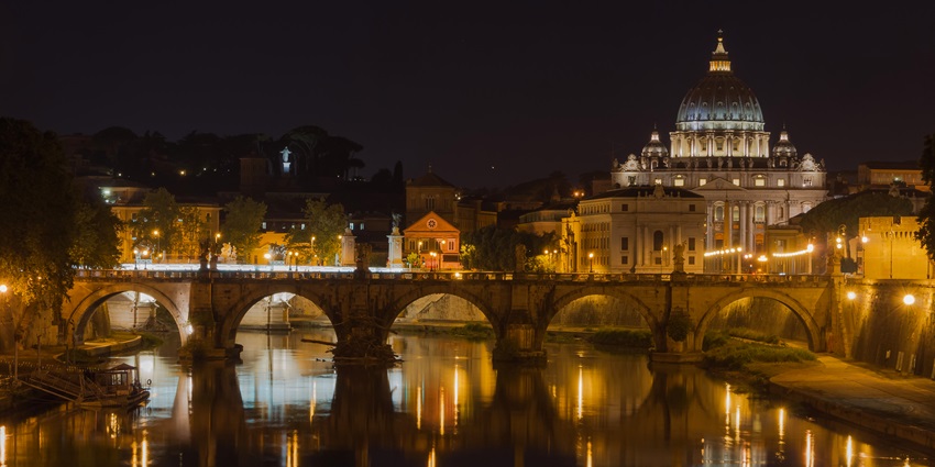 Rome's Castel Sant'Angelo at night, with the illuminated bridge and reflections on River