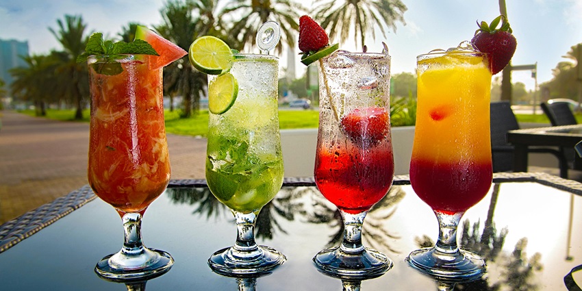 Four vibrant garnished cocktails on a reflective table, similar to Ruby Cocktail Bar menu.