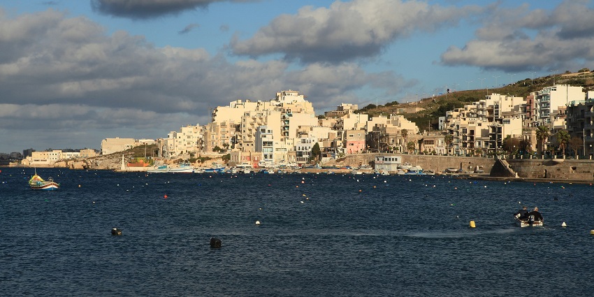 Image of Saint Paul’s Bay water near city buildings and people exploring on small boats