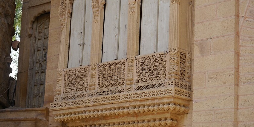 Closeup of a historic building with a finely detailed carved design and a door with stairs