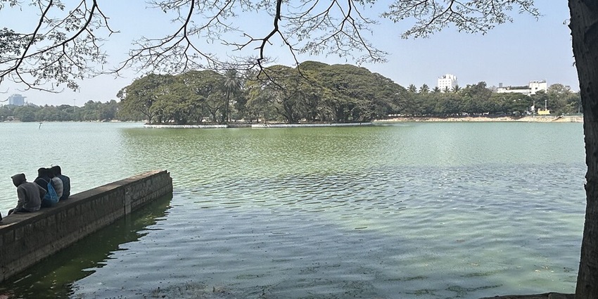 A group of people sit on a broken submerged wall in a beautiful lake.