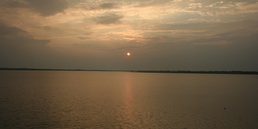 Image of a Lake during sunset with a person boating similar to lakes in Madhya Pradesh