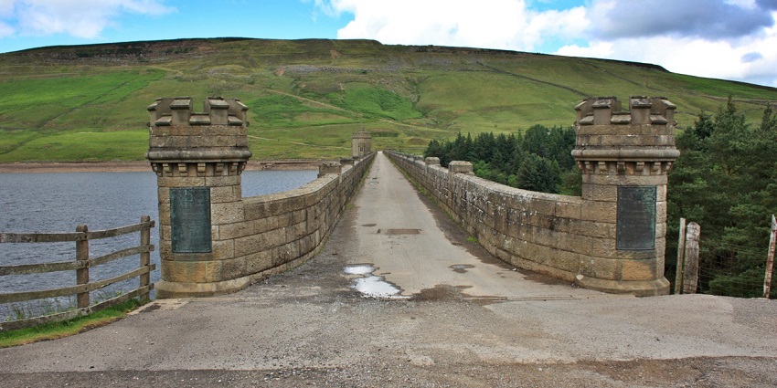 Dam Top Road at Scar House Reservoir with two for like structures and a long path