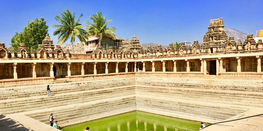Image of a pond inside the Prati Pandharpur Temple with tourists sitting around it.