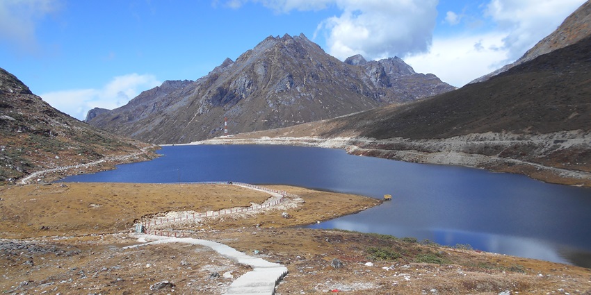 A panoramic view of the Sela Lake, one of the lakes in Arunachal Pradesh, surrounded by mountains and clear sky.