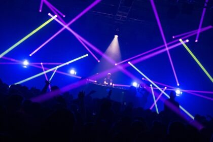 An inside view of a club adorned with gleaming lights and people dancing on the floor.