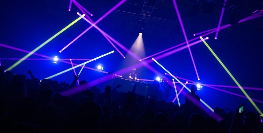 An inside view of a club adorned with gleaming lights and people dancing on the floor.