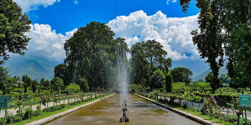 Panoramic view of Shalimar Bagh with a beautiful fountain, greenery and mountainous backdrop.