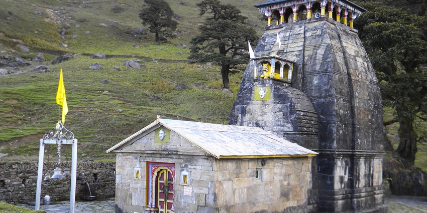 Madhyamaheshwar Temple surrounded by hills in Uttarakhand on a clear sunny day
