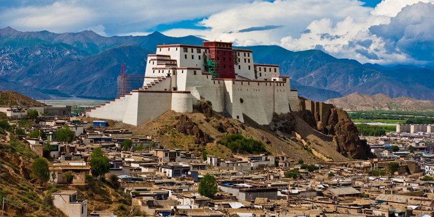 Shigatse Dzong, a historic fortress with towering walls, nestled amidst rugged mountains and clear skies