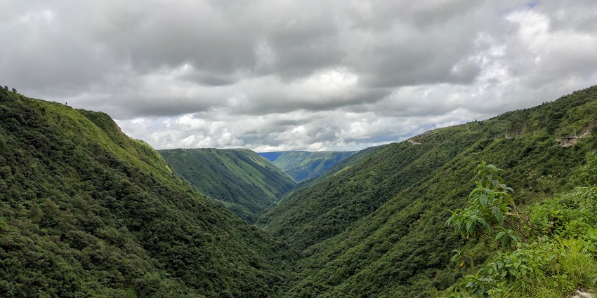 An image of a lush green valley nestled between steep hills, under a dramatic cloudy sky.