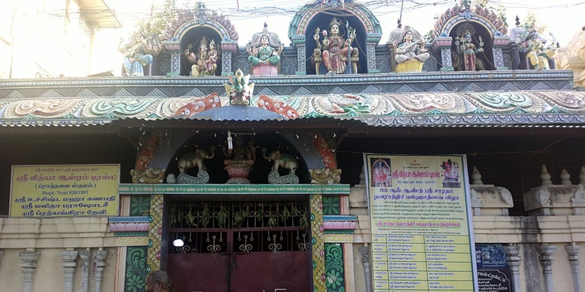 Entrance gate of the Sri Maha Prithyangira Devi temple with a priest standing outside
