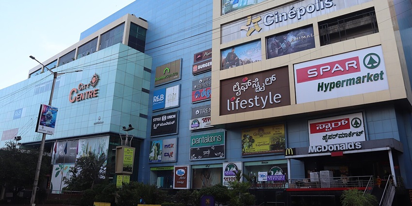 An open-air shopping plaza with people relaxing near the stepped amphitheatre “Kund” at City Centre 1 Mall in Salt Lake.