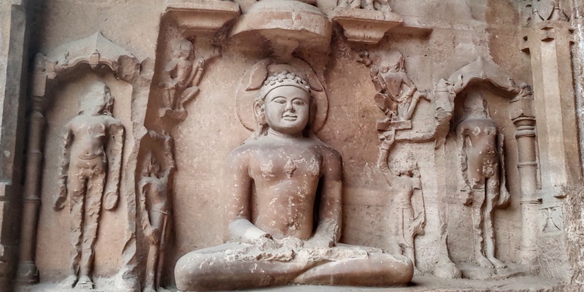 An image of Jain caves at Gwalior Fort, displaying large statues and complex carvings