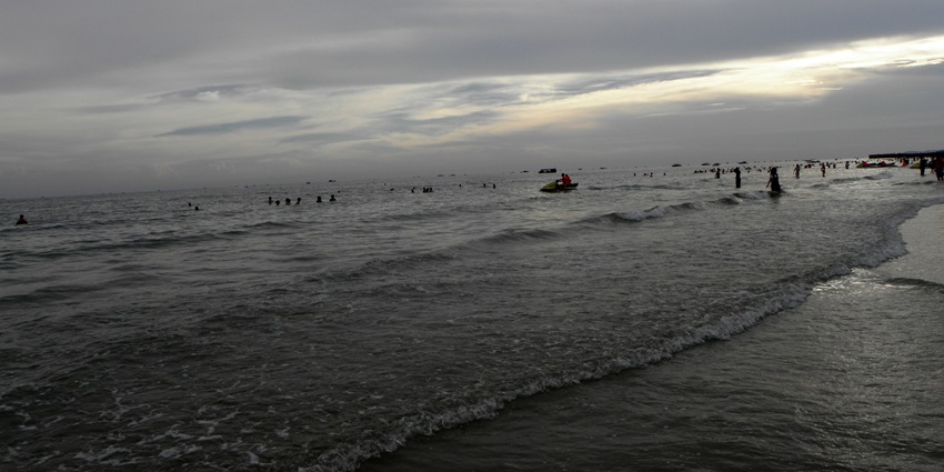 An image of Silver beach, with waves, a jet ski, and people wading in the water.