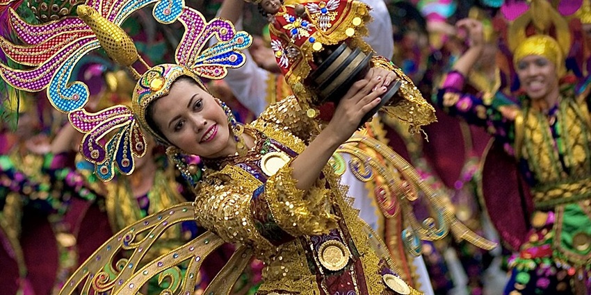 The Sinulog Festival has a street parade with dancers dancing to the beat of drums.
