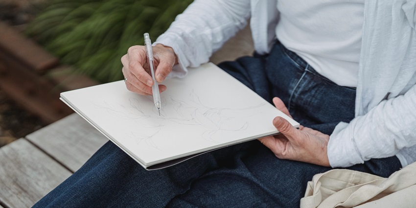 An artist sketching the Ulsoor Lake view with a notebook and pencil, one of the best things to do in Ulsoor lake.