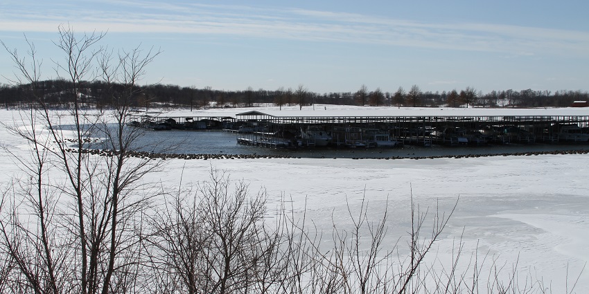 An image of Smithville Lake in a snowy landscape and dried-out trees with no leaves