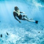 An image of a snorkeller surrounded by black fishes similar to snorkelling in India