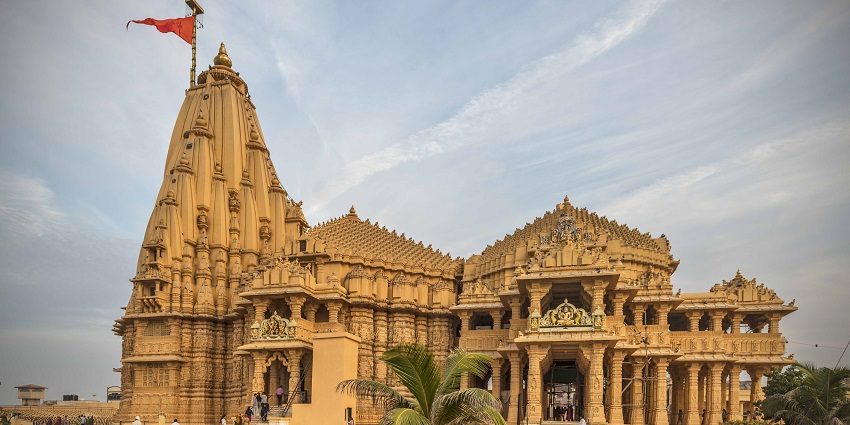 A side view of the Somnath Temple shows devotees climbing the stairs near its entrance.