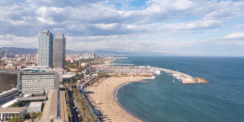 Aerial view of a beach and city building near - Soft sand and rolling waves at Somorrostro beach