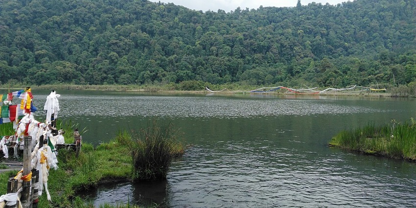Khechuperi Lake in the west Sikkim with the Buddhist flags on the left side and greenery.