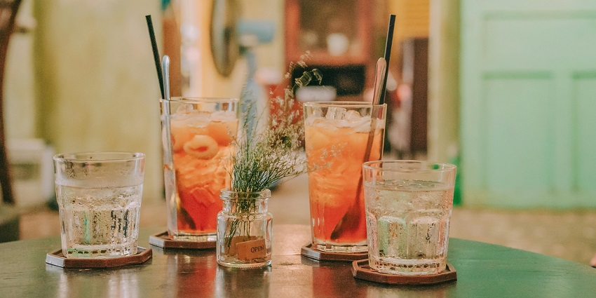 Four Clear Glass Drinking Cups Filled With Orange and Clear Liquids on Black Surface
