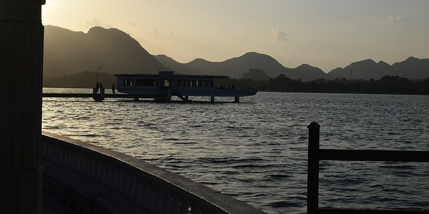 A tranquil waterbody at Nehru Garden, surrounded by lush greenery and distant mountains