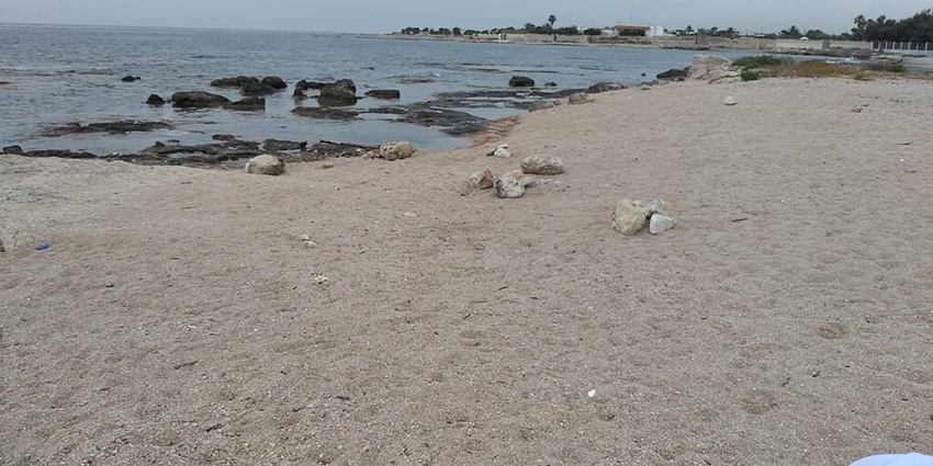 Peaceful view of Spiaggia Di Mola Di Bari, a combination of sand and rocks.