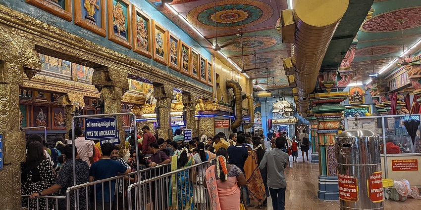 Interior of the Vinayagar temple with people waiting in line for darshan and signboards