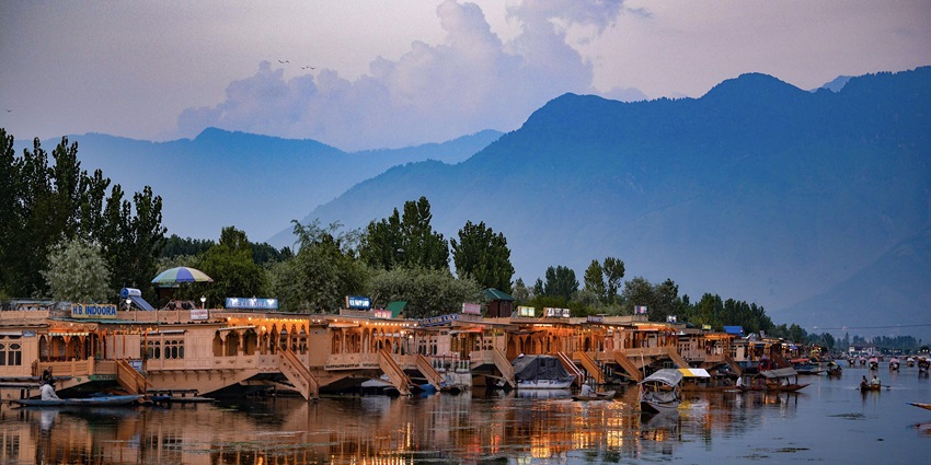 An image of the serene Dal Lake in Srinagar with houseboats and snow-clad mountains.